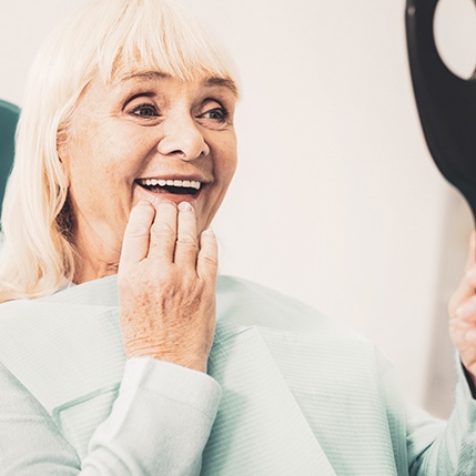 a dentures patient admiring her smile 