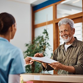 front desk associate giving a patient his paperwork