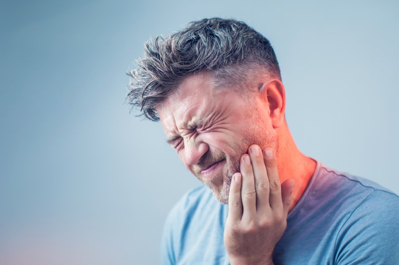 person experiencing dental emergency holding cheek